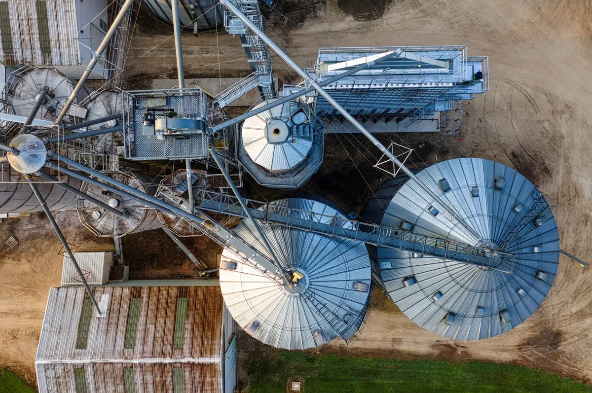 Drone shot of metal grain silos in Utica, MN, showcasing industrial agriculture.