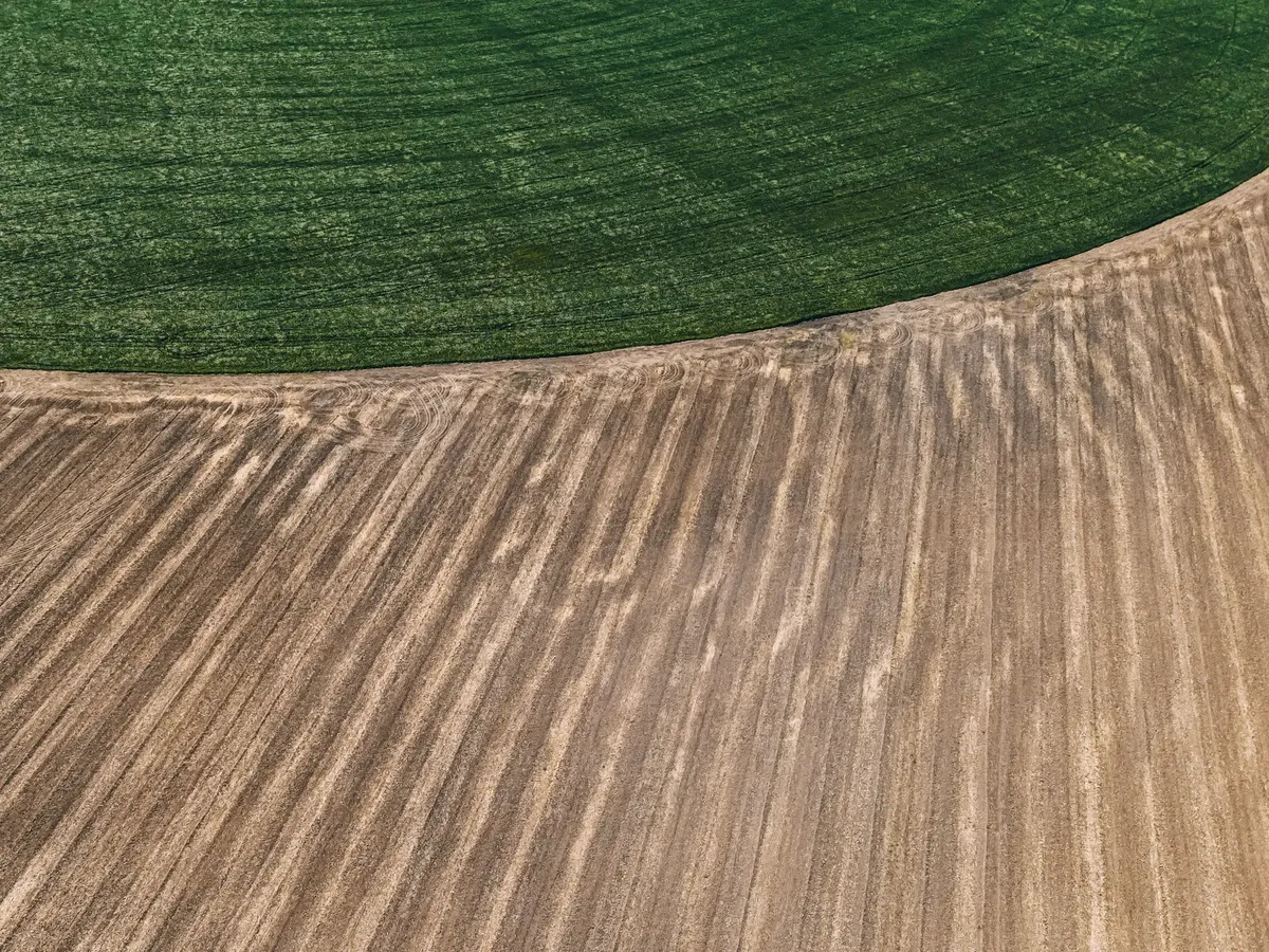 Drone shot showcasing agricultural patterns in green and brown fields.
