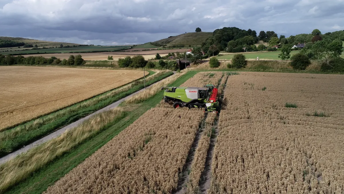 Drone view of a combine harvester on a rural farm in Bishopstrow, England.